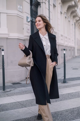 a lady in a white shirt, a pair of brown pants and a black long coat